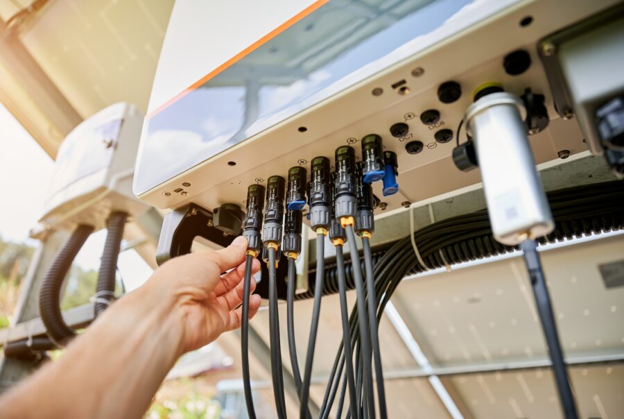Professional worker connecting wires to solar inverter